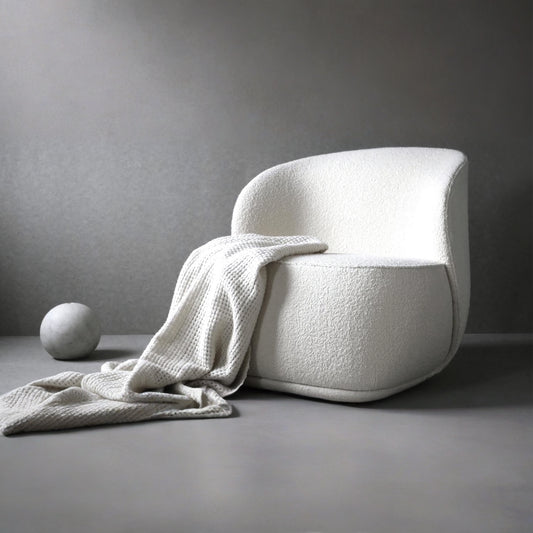 White textured chair with a blanket draped over it against a gray background